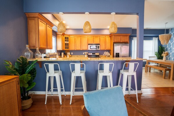 Une cuisine moderne avec des meubles en bois, un îlot central doté de tabourets de bar et des luminaires suspendus.