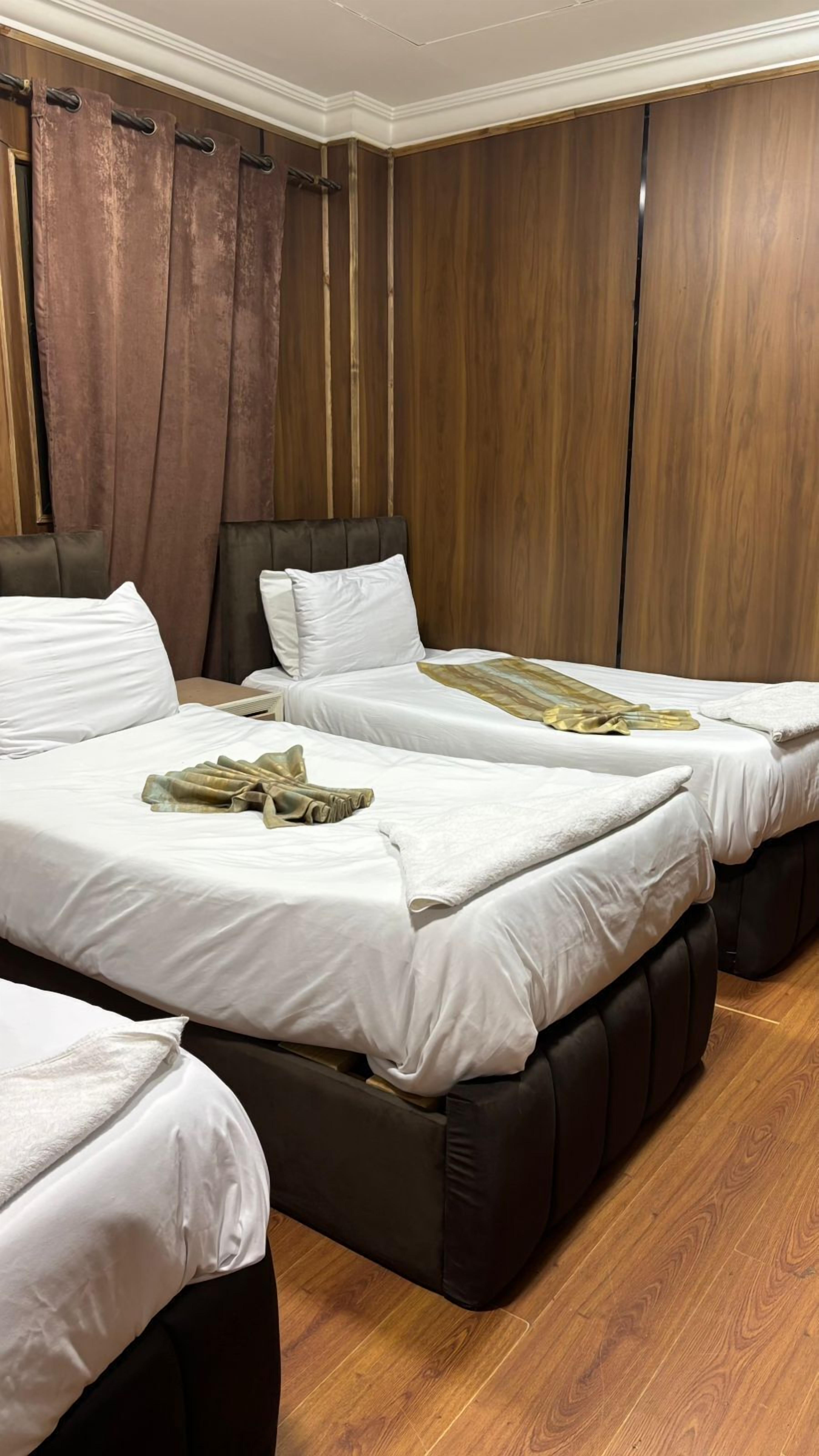 A hotel room with two beds, wooden panel walls, and a wooden floor.