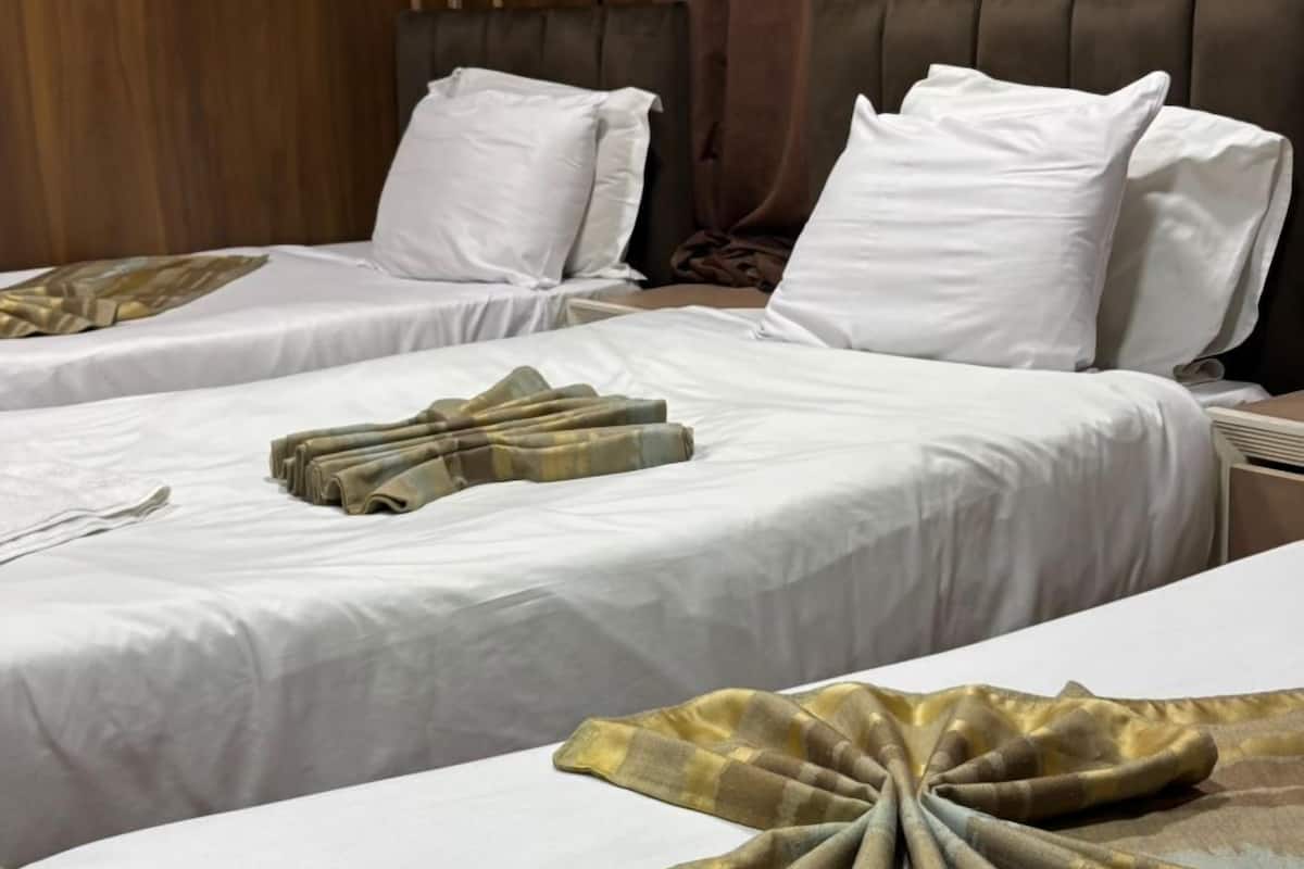 Habitación de hotel con dos camas, un panel de pared de madera y un equipo de aire acondicionado.