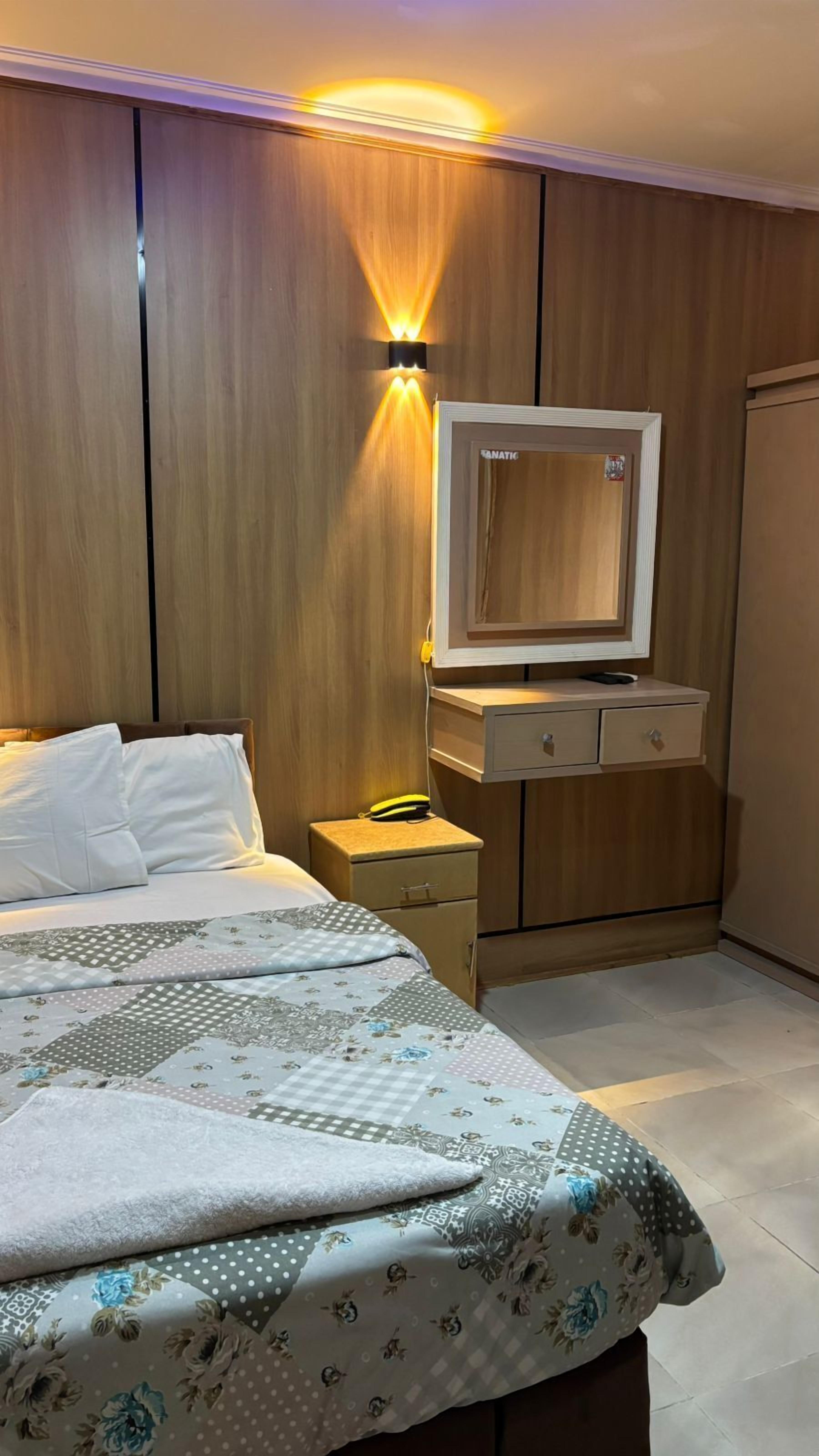 Ein Schlafzimmer mit Bett, Nachttisch, Kleiderschrank und einem an der Wand befestigten Fernseher.
