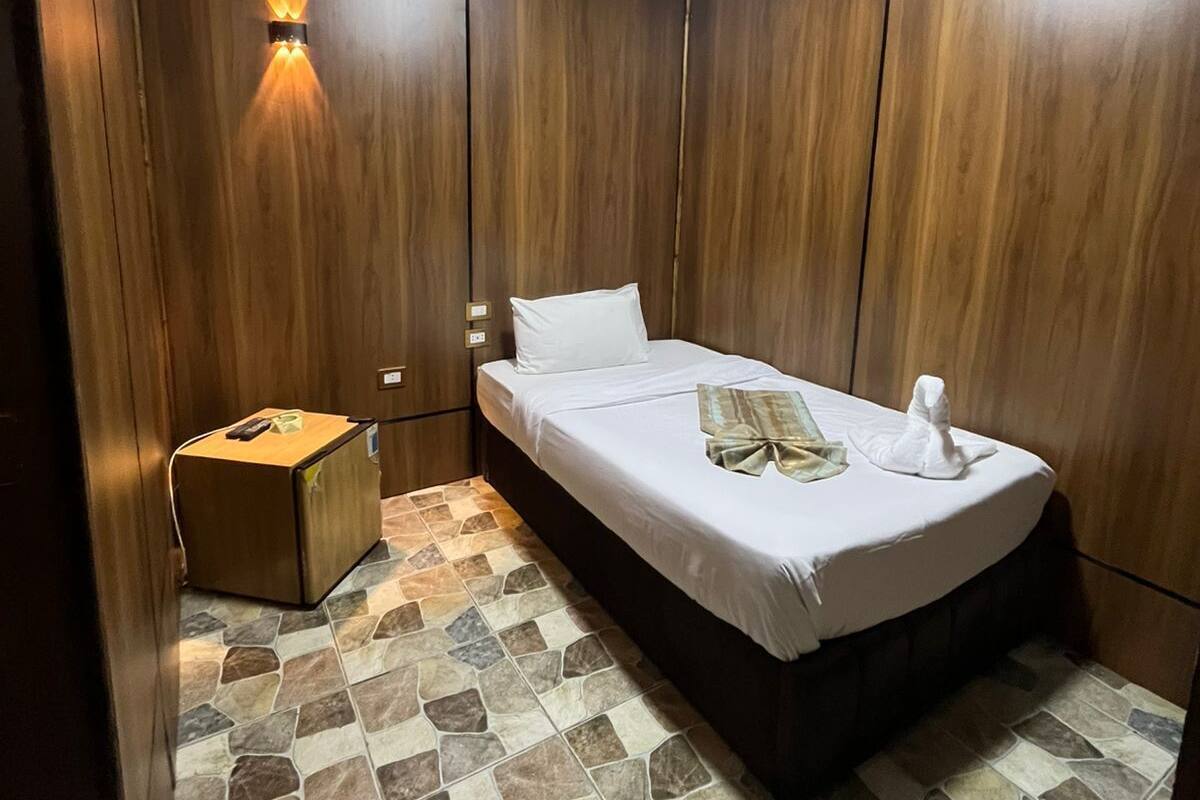 Un dormitorio con cama, mesita de noche, luz empotrada en la pared y suelo de baldosas.