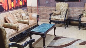 Una sala de estar con sofá, sillones, una mesa de centro, un televisor de pantalla plana en la pared y un mural grande.