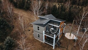 Ein modernes, zweistöckiges Haus mit Balkon, umgeben von Bäumen.