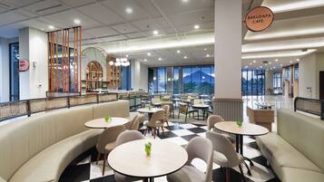 A modern cafe with a checkered floor, round tables, and cushioned seating areas.