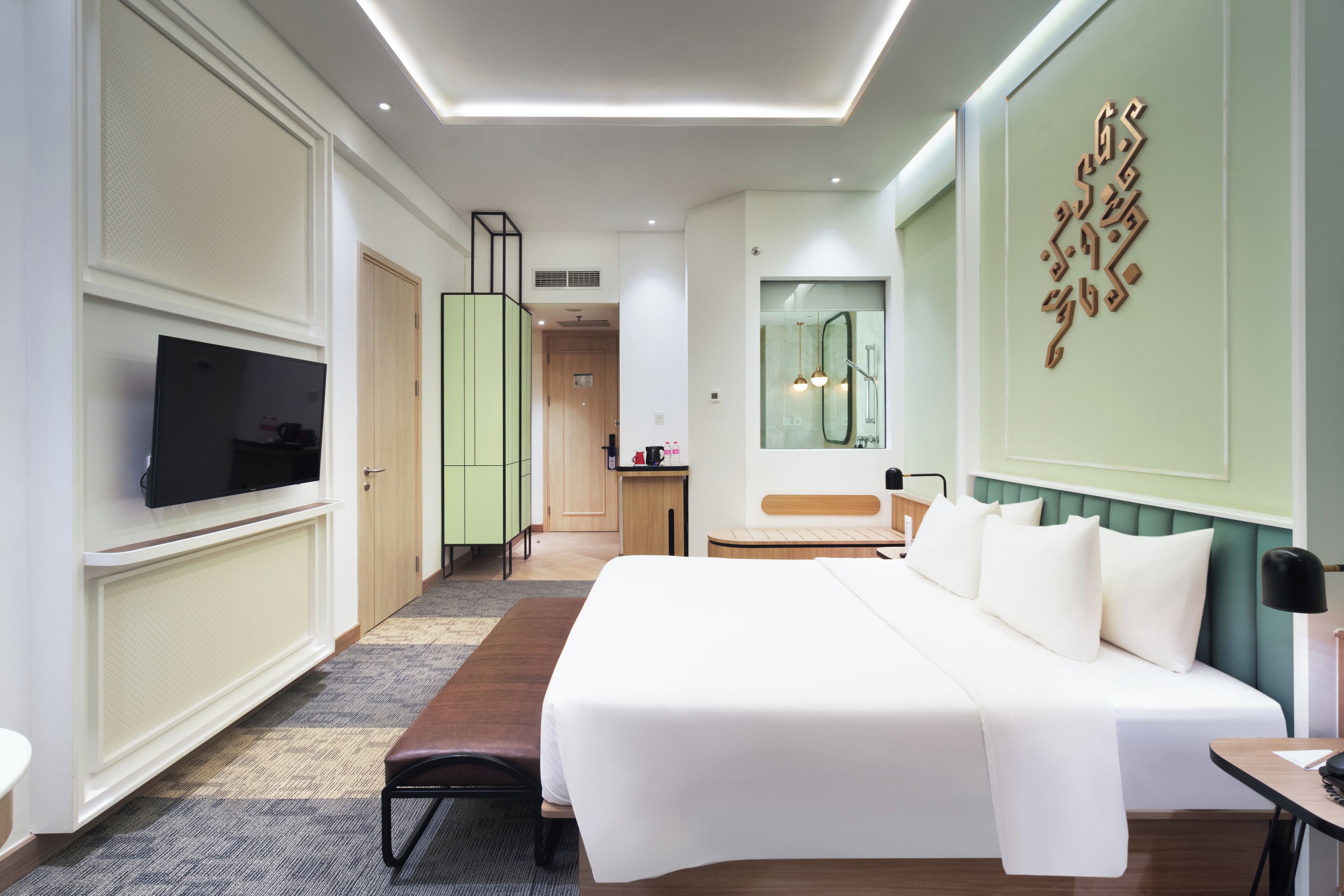 A modern hotel room with a large bed, a flat-screen TV, a desk, and a bathroom with a mirror and shower.