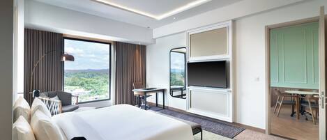 A hotel room with a large bed, a desk, a chair, a TV, and a view of the outdoors.