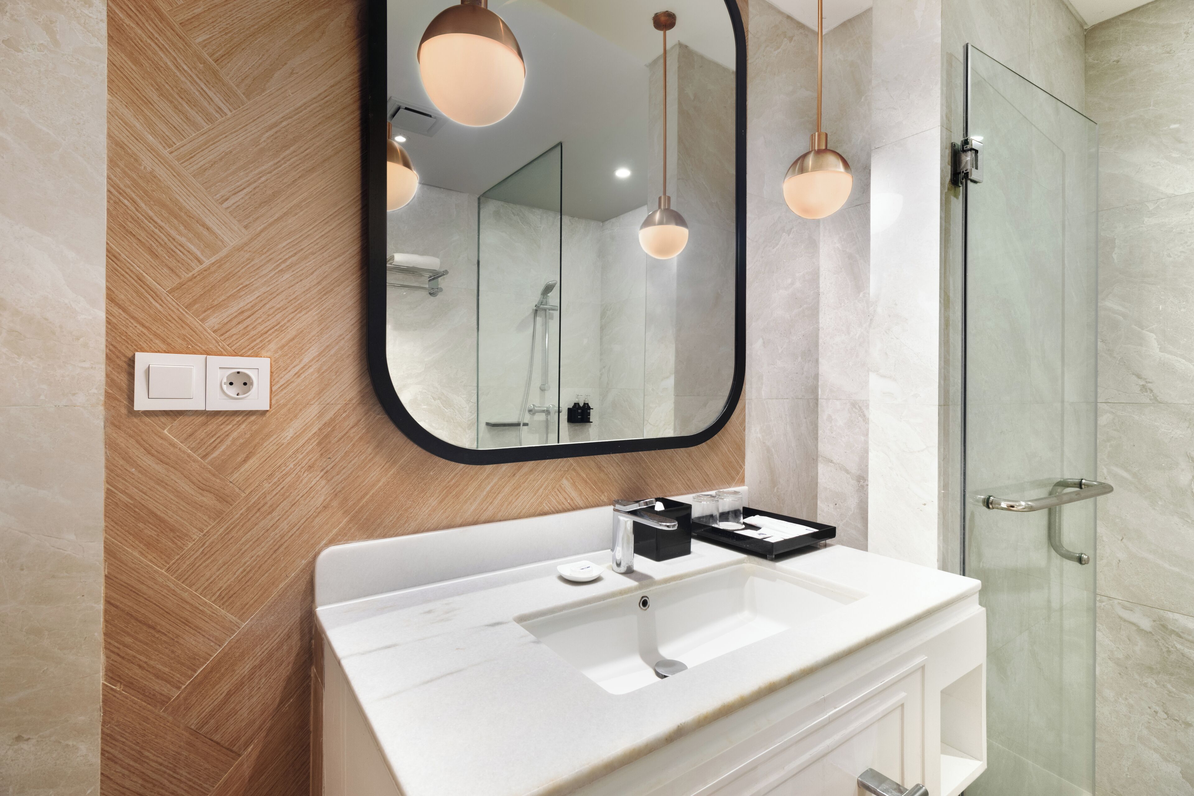 A modern bathroom with a white sink, a large mirror, and a glass shower enclosure.