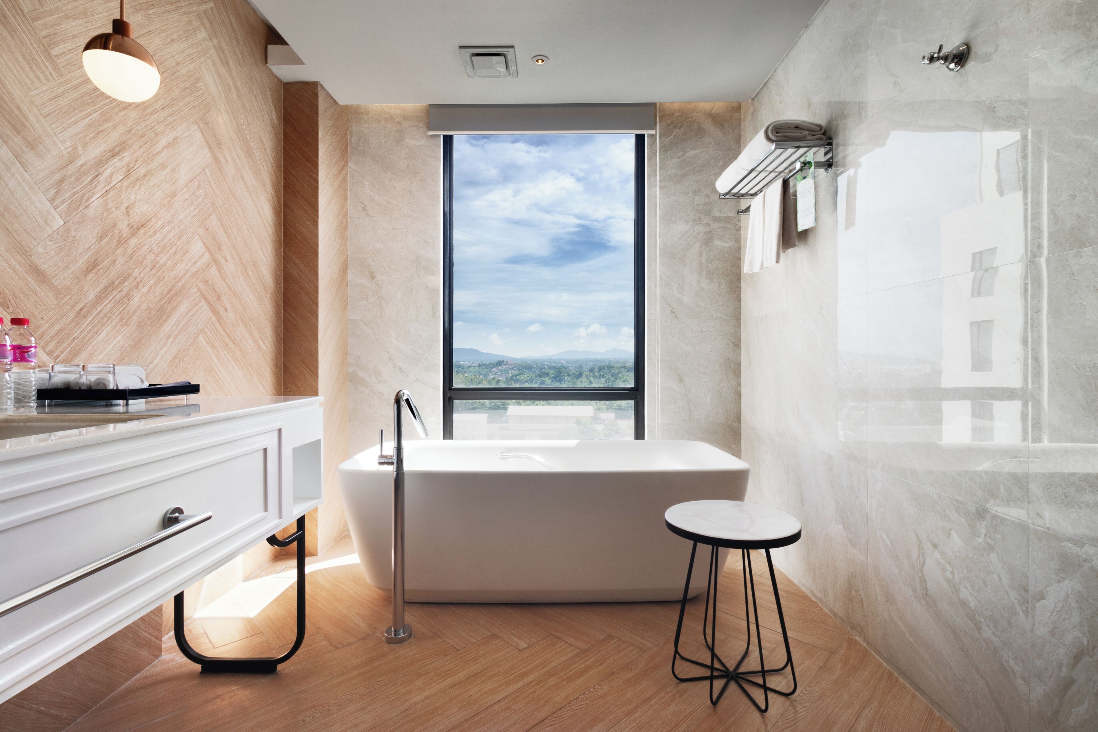 A modern bathroom with a freestanding bathtub, a large window offering a city view, and a minimalist design.
