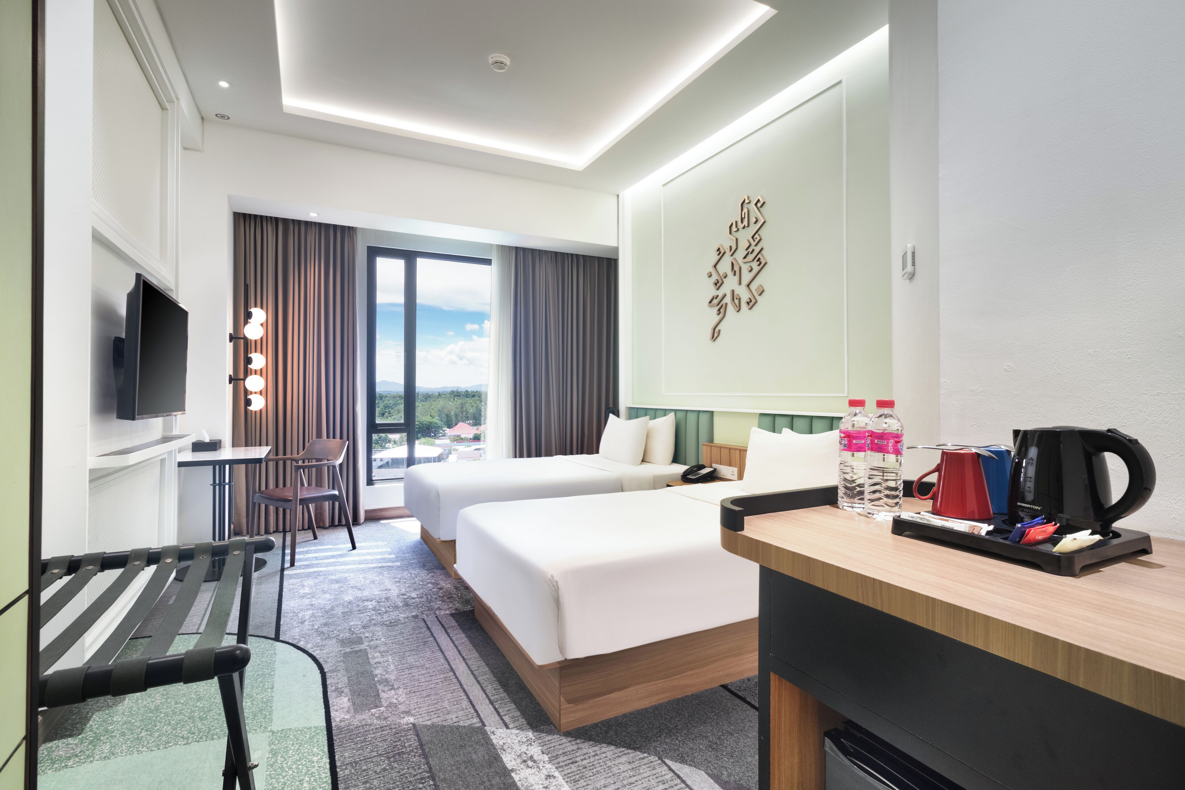 Hotelkamer met twee bedden, een bureau, een stoel, een televisie, een raam met uitzicht en een decoratief object aan de muur.