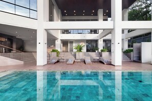 A modern indoor pool area with a clear view of the pool, lounge chairs, and a sign reading "KIDS". - Luwansa Hotel & Convention Center Manado (Manado)