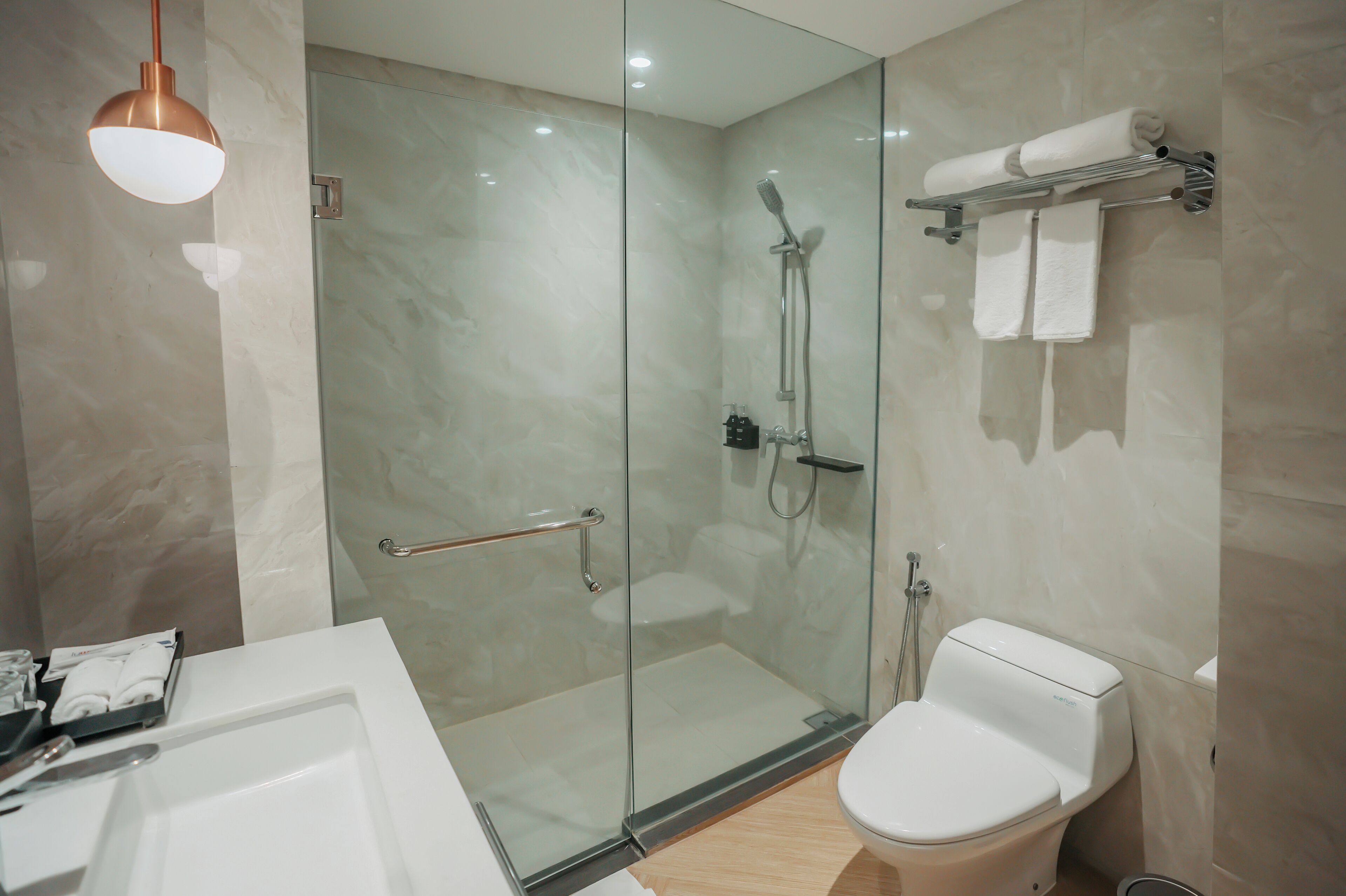 A modern bathroom with a glass-enclosed shower, a white toilet, and a glass-enclosed bathtub.