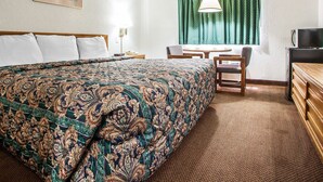 Une chambre d’hôtel avec un grand lit, un bureau avec une chaise, une télévision et une fenêtre avec des rideaux.