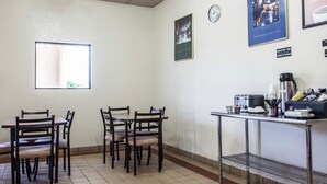 Un coin repas avec une table et des chaises, une horloge et une affiche accrochée au mur.