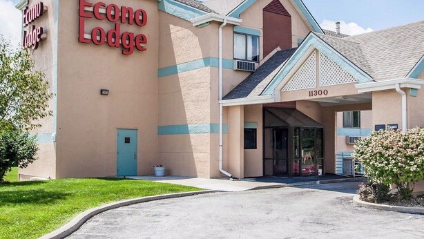 Un hôtel appelé Econo Lodge, avec une façade beige, une porte bleue et un ciel dégagé.