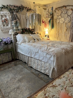 Un dormitorio con una cama grande, adornos florales y varias prendas colgadas.