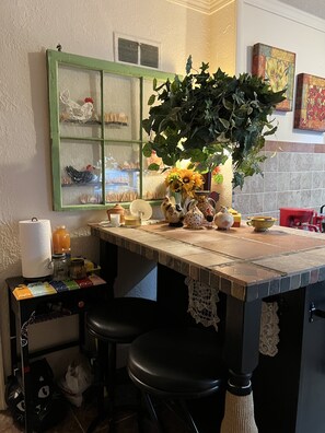 Una cocina con un espejo de marco verde, una planta en maceta y diversos utensilios de cocina sobre la encimera.