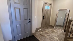 A hallway with a grey door, a door with a window, and a mirror on the wall. - Three Bedroom House,  sleeps 7 (Edmonton)