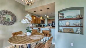 A dining area with a round wooden table, cushioned chairs, and a decorative mirror on the wall.