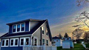 A two-story house with a front deck, a garage, and a small shed in the background. - Beach Ready 3-bdrm house, Short Walk to Private Beach and Park, Lots of Parking (Niantic)