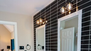 Ein modernes Badezimmer mit zwei Waschbecken, Wandfliesen in Schwarz und Weiß und einem großen Spiegel.