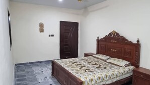 Quarto com cama de madeira, mesa de cabeceira, guarda-roupa e ventoinha no teto.