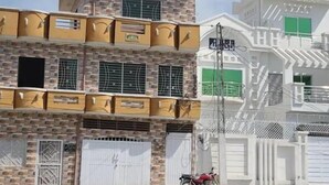 Um edifício com várias andares, varandas e portão.