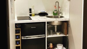 A compact kitchenette with a built-in refrigerator, a sink, and a small shelf with kitchen essentials. - Private Room - Sleeps 2 - Private Entry - Parking (Solihull)