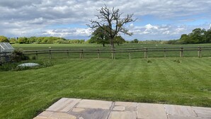 A stone patio leading to a grassy field with a wooden fence and a tree in the center. - Private Room - Sleeps 2 - Private Entry - Parking (Solihull)