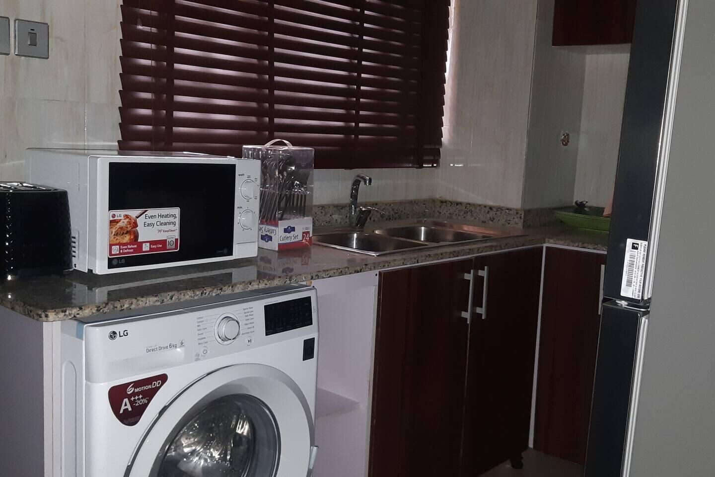 Une cuisine compacte équipée d’un lave-linge, d’un four à micro-ondes et d’un évier.