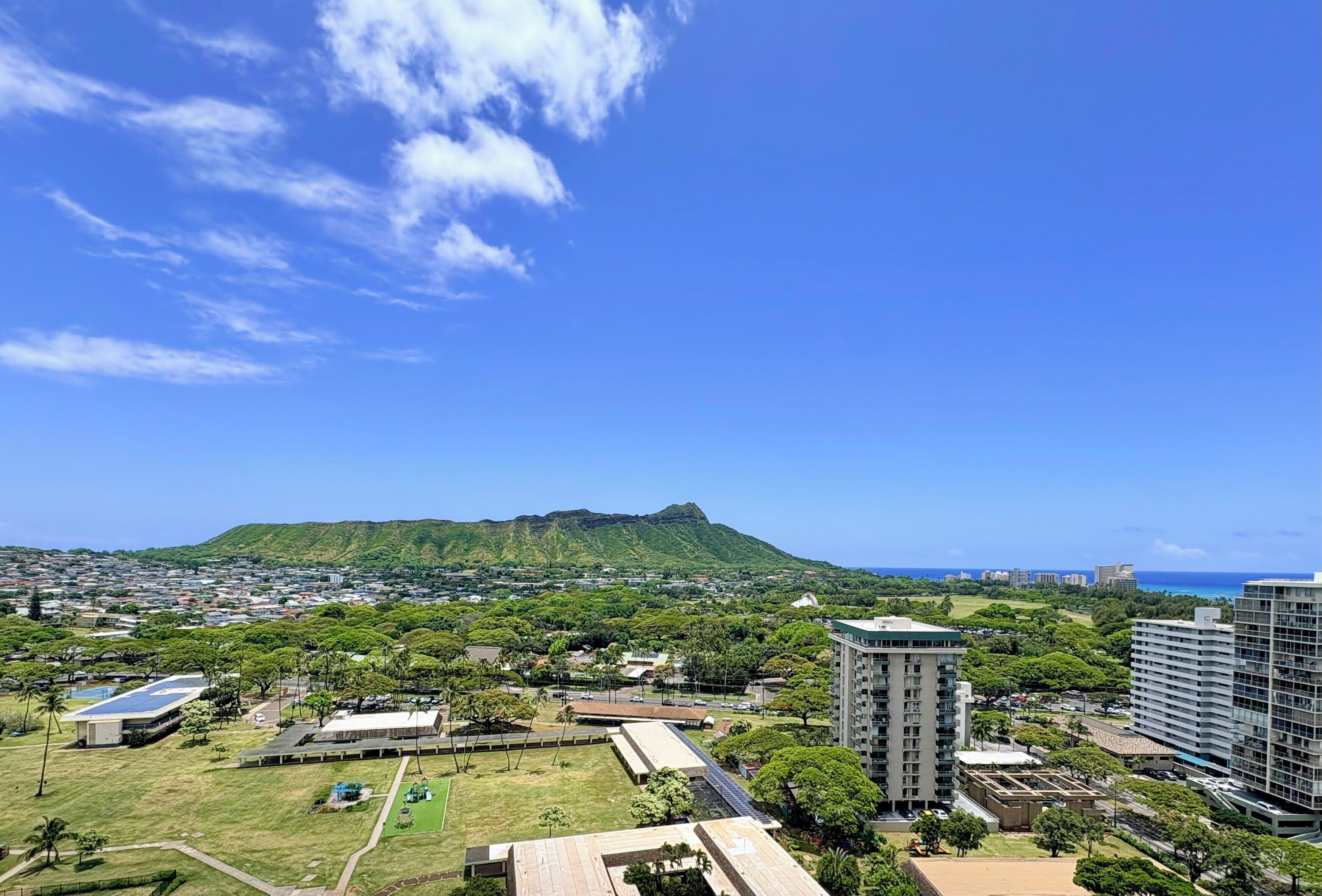 A cityscape with a prominent hill, buildings, and a clear sky.