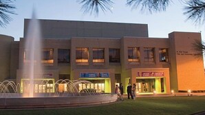 A building with a fountain in front, multiple signs indicating various services, and a well-lit entrance. - Dreaming Rose City Getaway! (Tyler)