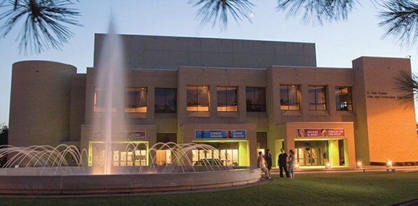 A building with a fountain in front, multiple signs indicating various services, and a well-lit entrance.