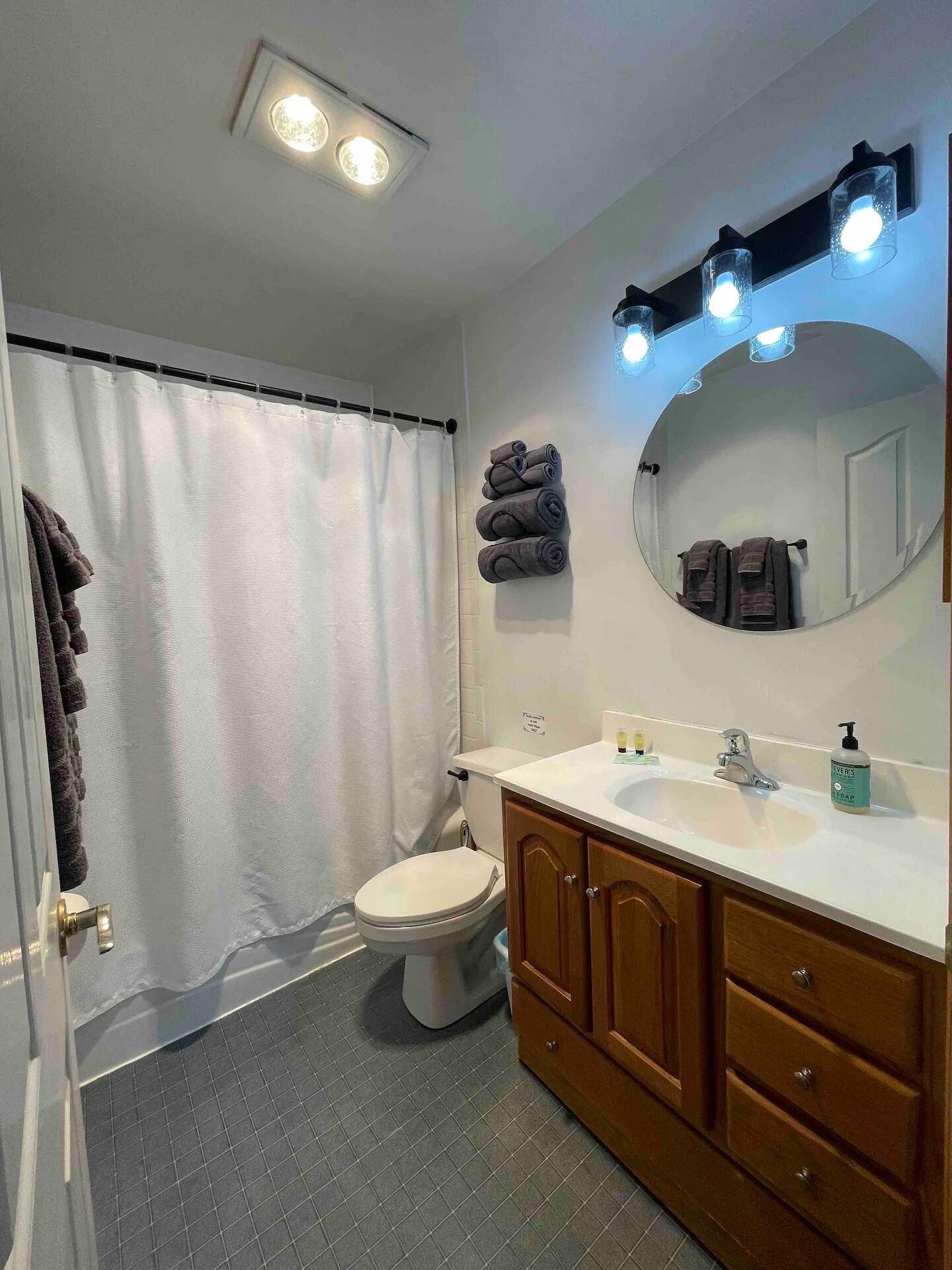 Une salle de bain avec des toilettes, un lavabo avec un miroir et un rideau de douche.