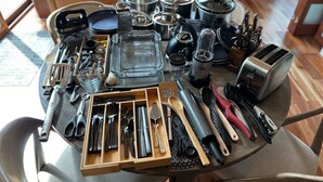 A table with various kitchen utensils and appliances, including a toaster, a coffee maker, and a variety of spoons and spatulas.