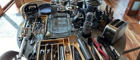A table with various kitchen utensils and appliances, including a toaster, a coffee maker, and a variety of spoons and spatulas.