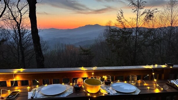 A table set for three with a view of mountains in the background.