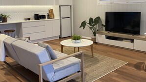 A modern living room with a sofa, a TV, and a ceiling fan.