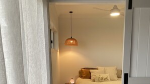 A bedroom with a bed, a bedside table, a lamp, and a ceiling fan.