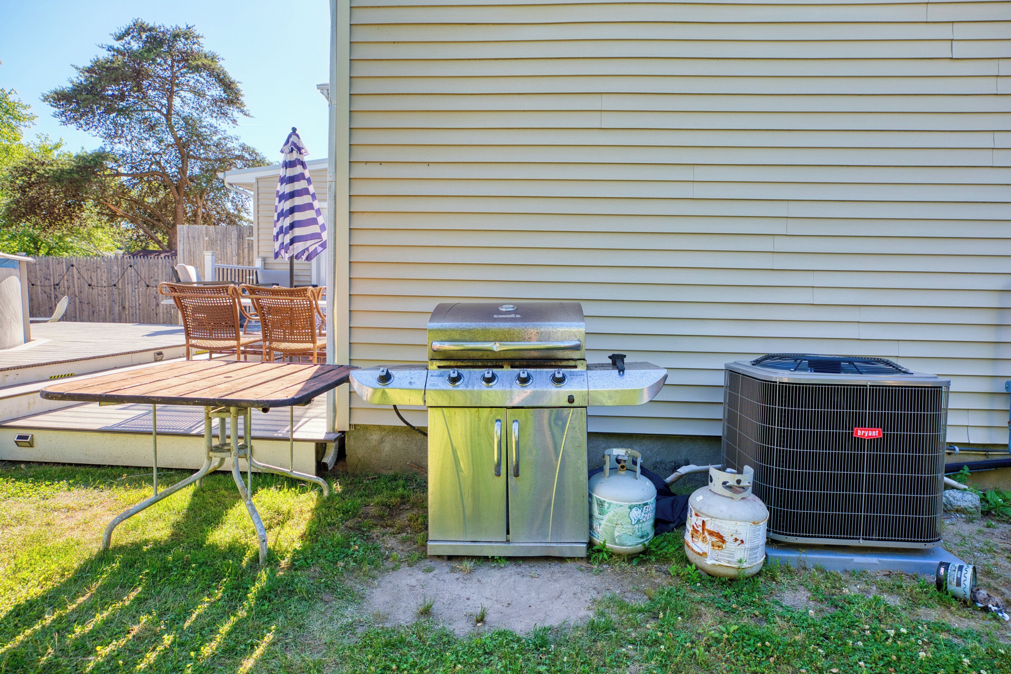Un jardin avec un barbecue, une table, des chaises et un appareil de climatisation.