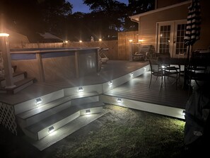 Een terras met treden naar een zwembad, omgeven door een houten omheining en tuinmeubilair.