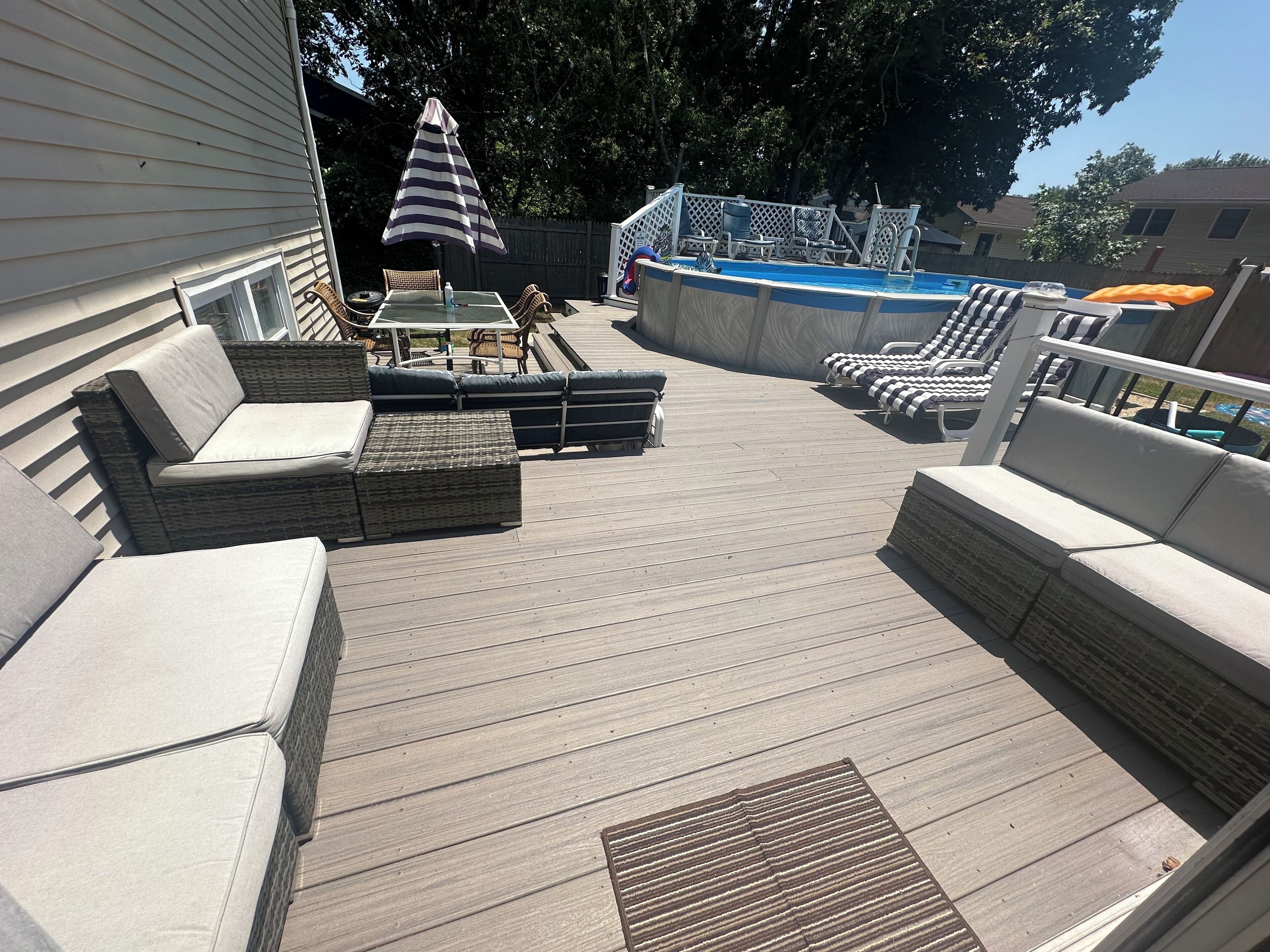 A deck with outdoor furniture, a pool, and a slide.