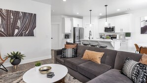 Ein modernes Wohnzimmer mit einem grauen Sofa, einem weißen Couchtisch und einer großen Sukkulente.