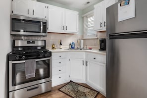 A modern kitchen with white cabinets, stainless steel appliances, and a built-in microwave.