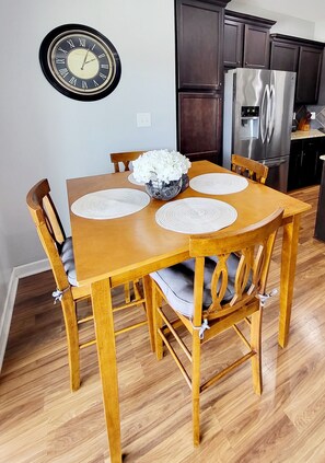 A wooden dining table with placemats, chairs, and a clock on the wall. - 🌟"Home-Away-From-Home" Beauty; Kid, Baby & Dog-Friendly; Veteran-Owned🌟 (Sanford)