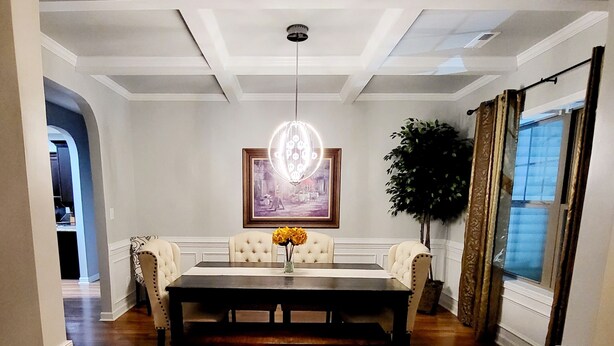 A dining area with a wooden table, cushioned chairs, a chandelier, and a framed picture on the wall. - 🌟"Home-Away-From-Home" Beauty; Kid, Baby & Dog-Friendly; Veteran-Owned🌟 (Sanford)