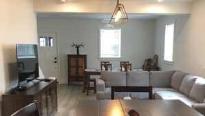 Un salon moderne avec un coin repas, des meubles en bois et un luminaire au plafond.