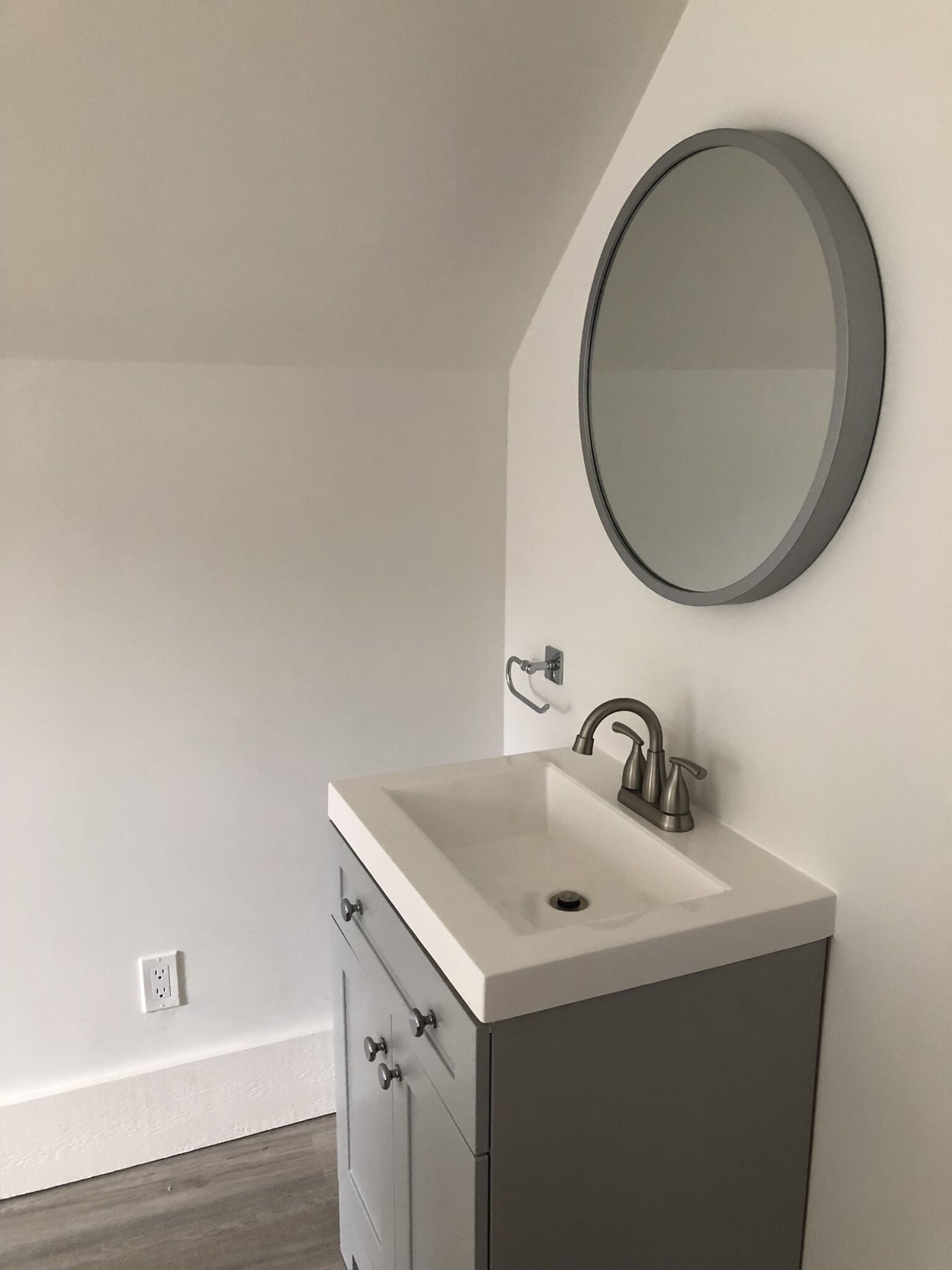 Un baño con tocador blanco, lavamanos, espejo y grifo.