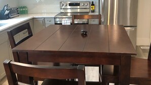 Une cuisine moderne dotée d’appareils électroménagers en acier inoxydable, d’une table à manger en bois et de meubles de rangement de couleur claire.