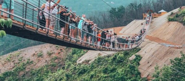 A suspension bridge with people walking across it. - Cozy Cabin Hot tub Firepit Game Room Pool Table Gas Fireplace 5 min to GB-PF (Sevierville)