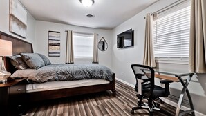 Een slaapkamer met een bed, een bureau en een stoel.